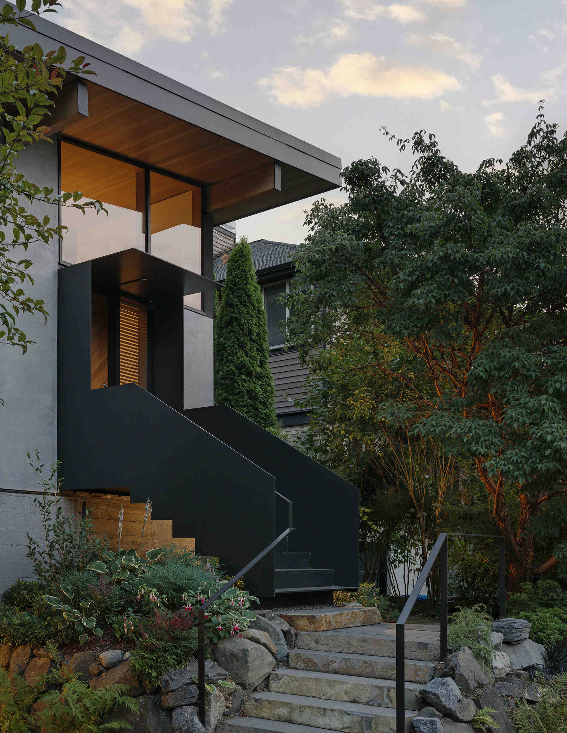 Elevated entry with stairs leads to a light-filled Seattle home with high shed roof and clerestory windows