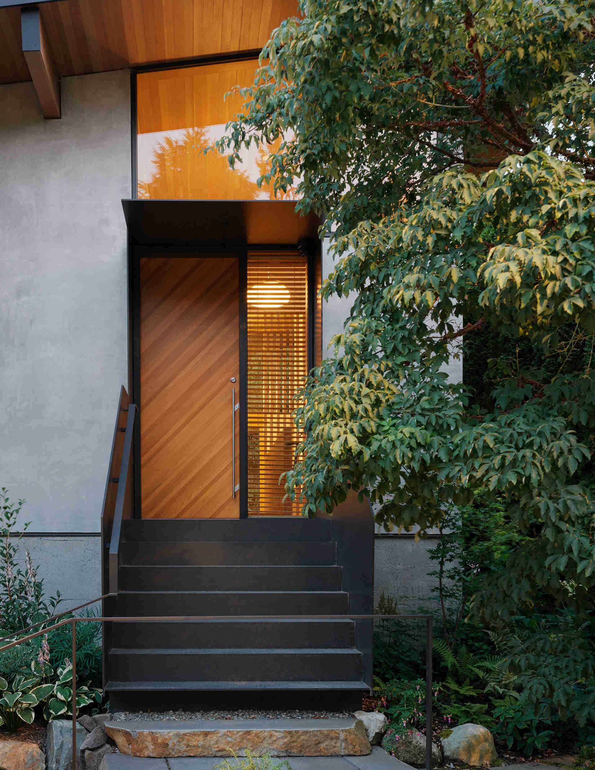Elevated entry with stairs leads to a light-filled Seattle home with high shed roof and clerestory windows