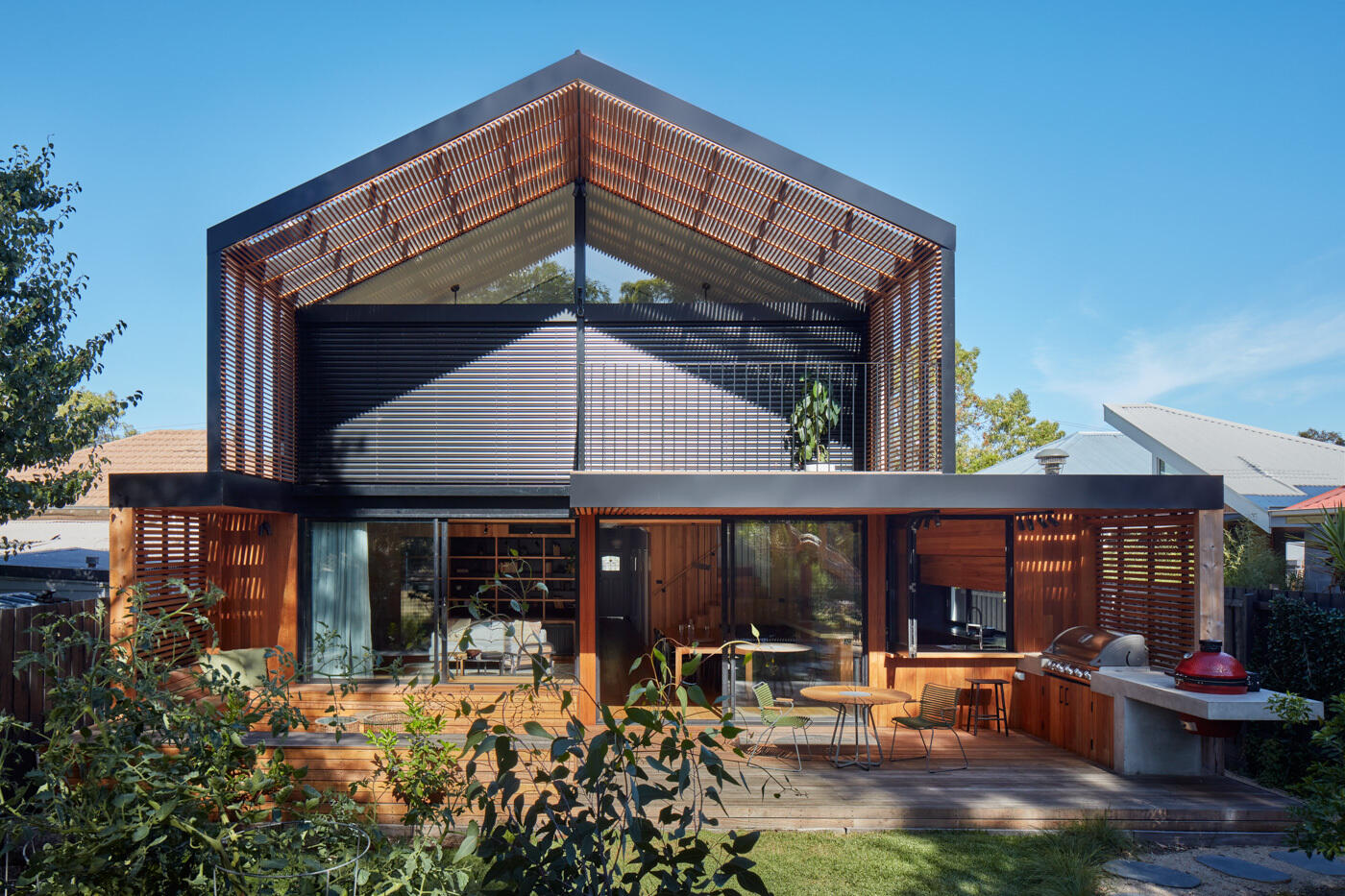 La extensión abre la casa al patio trasero y al parque más allá, creando claras conexiones visuales y espaciales con el paisaje. Las grandes aberturas, las pantallas envolventes de madera y las rejillas permiten que el aire y la luz fluyan libremente, creando una sensación de confort natural durante todo el día.