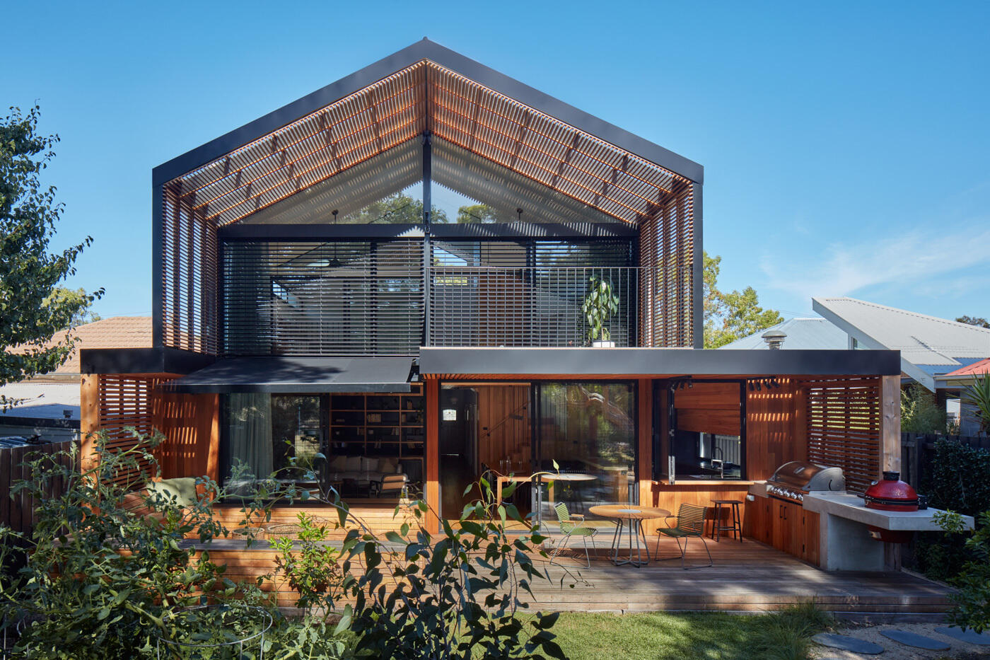 La extensión abre la casa al patio trasero y al parque más allá, creando claras conexiones visuales y espaciales con el paisaje. Las grandes aberturas, las pantallas envolventes de madera y las rejillas permiten que el aire y la luz fluyan libremente, creando una sensación de confort natural durante todo el día.