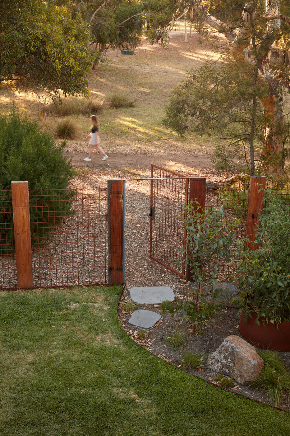 La valla trasera transparente permite vistas sin obstáculos del parque. En lugar de cerrar la frontera, la extensión abarca su exposición. La plantación en capas y las formas construidas suavizan esta relación, creando profundidad y privacidad sutil sin bloquear completamente la vista.