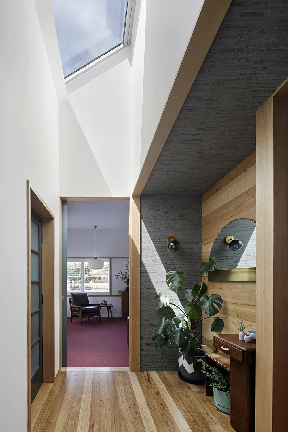 A skylit hallway links the new addition to the original home, with timber flooring adding warmth and continuity throughout.