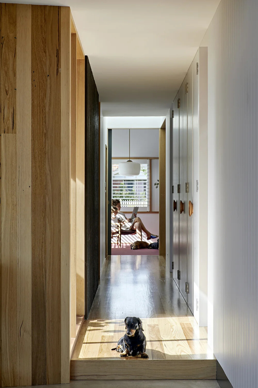 A skylit hallway links the new addition to the original home, with timber flooring adding warmth and continuity throughout.