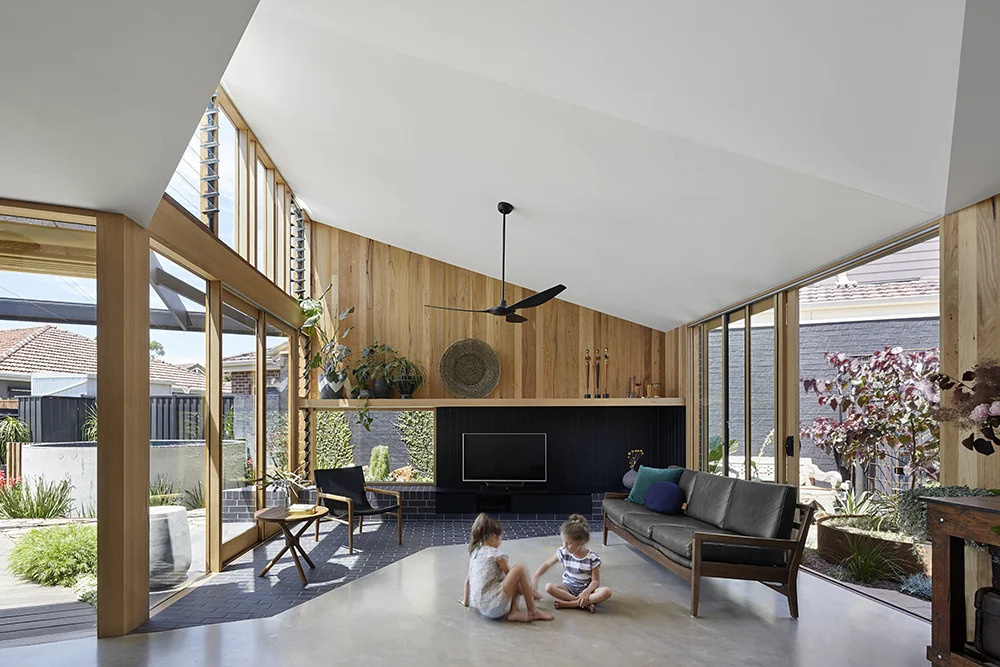 High ceilings, natural light, and dark brick flooring create a living room that feels open, calm, and connected to the garden.