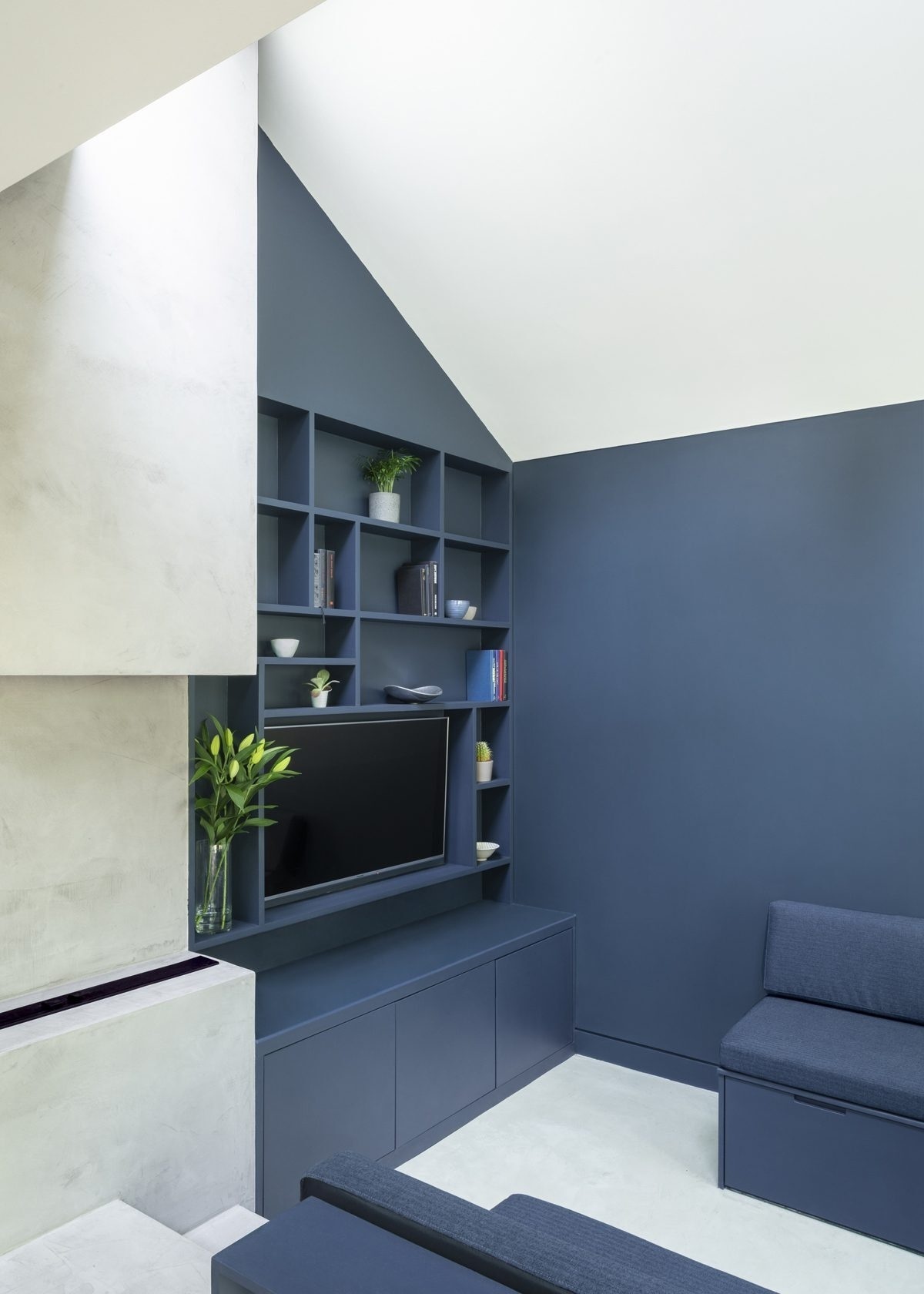 Las paredes de color azul oscuro, las estanterías empotradas y un sofá en forma de U crean una sala de estar íntima pero elegante.