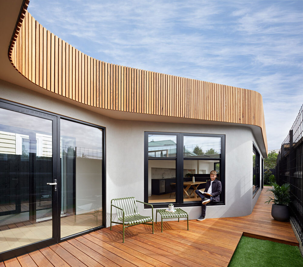 A sculptural timber facade curves into the garden, with planting set to create a future wall of green.