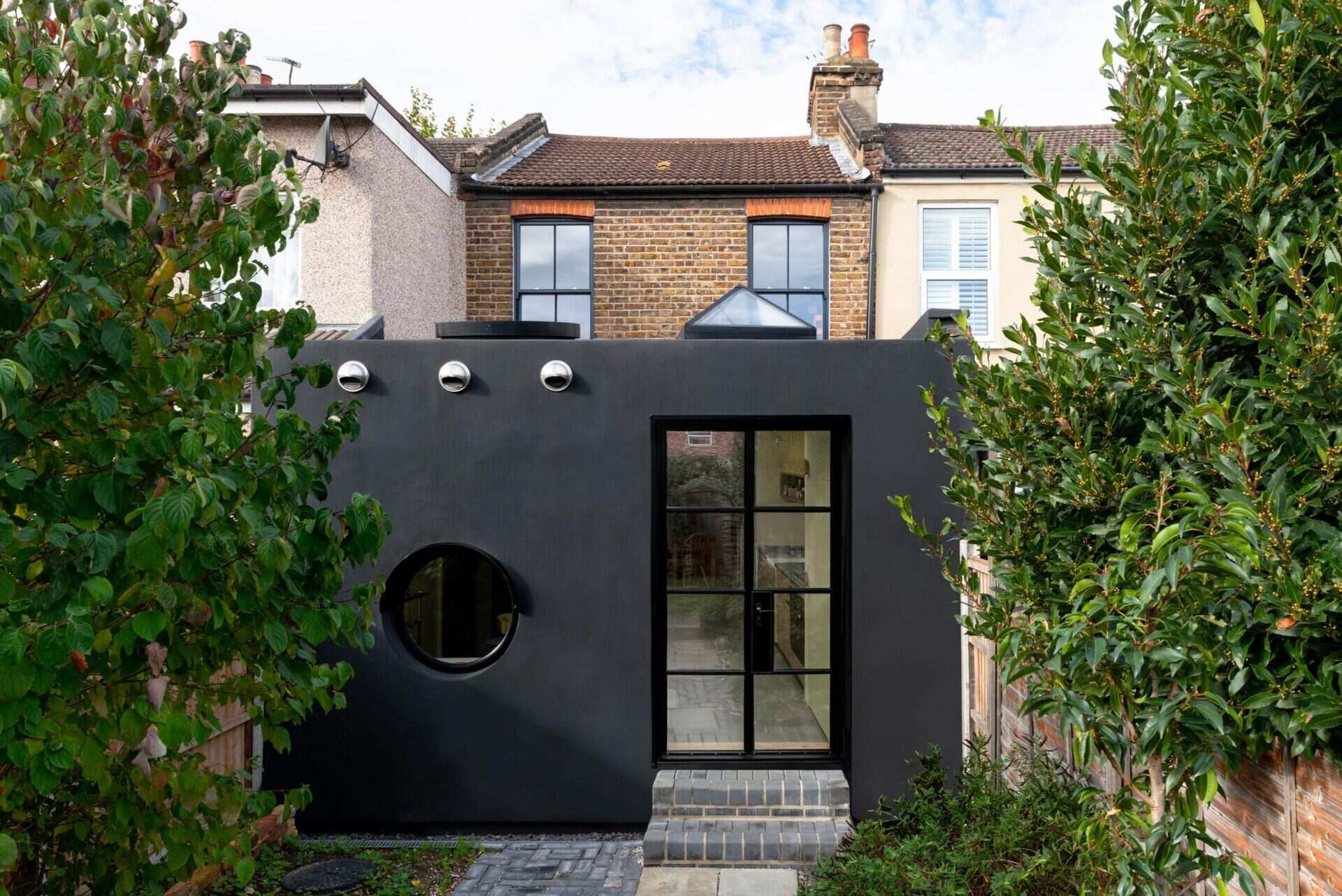 This modern black London home extension is coated in Prokol polyurea, a seamless industrial rubber chosen for durability, low cost, and visual impact.