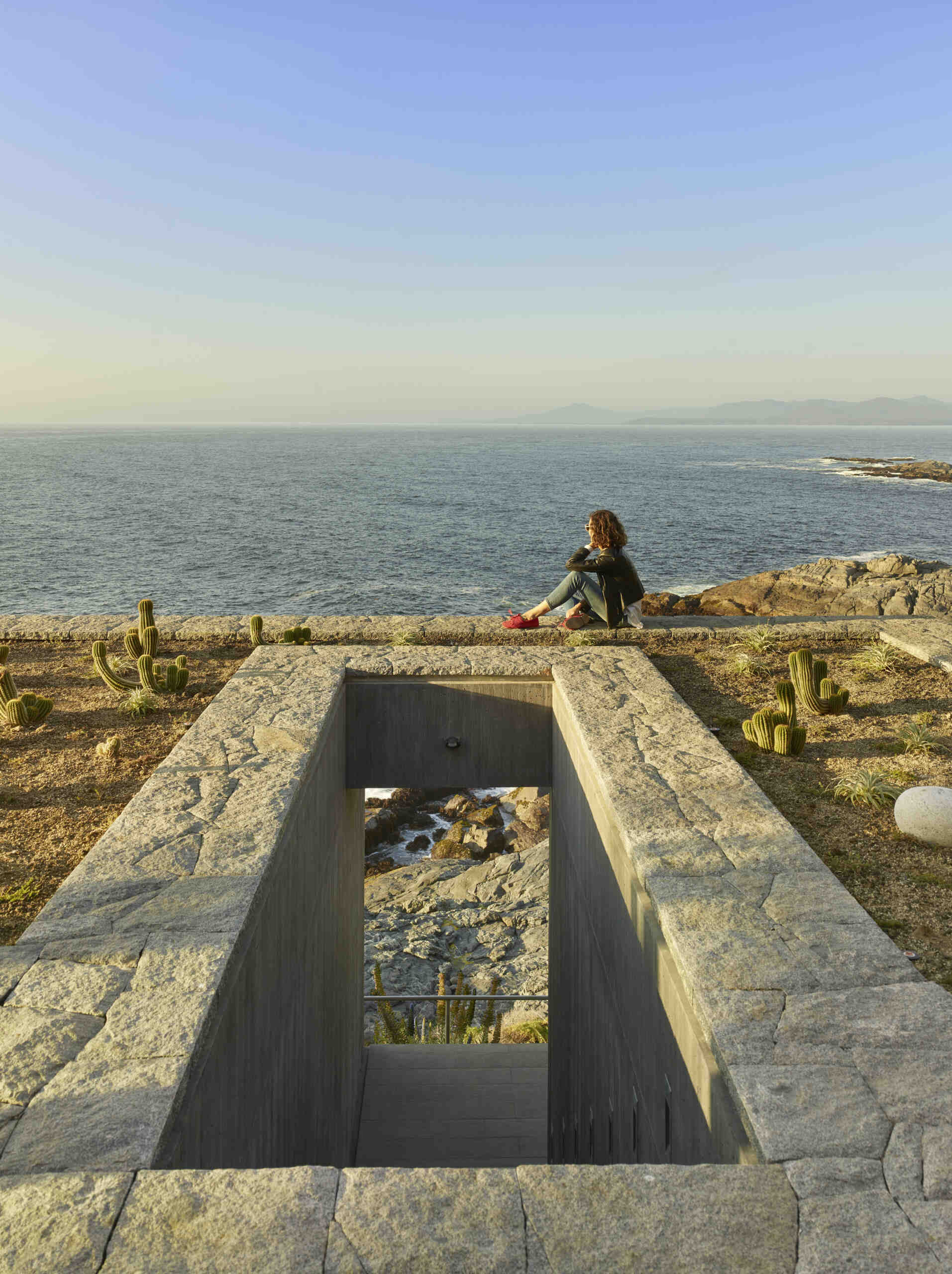 A green roof helps the concrete base blend into the rocky landscape, reducing the visual presence of the house.