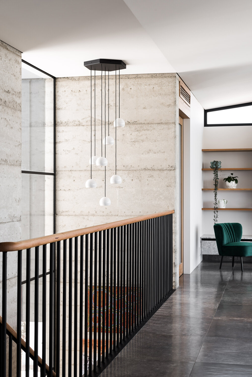 Rammed concrete, limestone and timber create a calm, grounded interior inside this East Fremantle home, with black steel and wood stairs leading to the main living spaces.