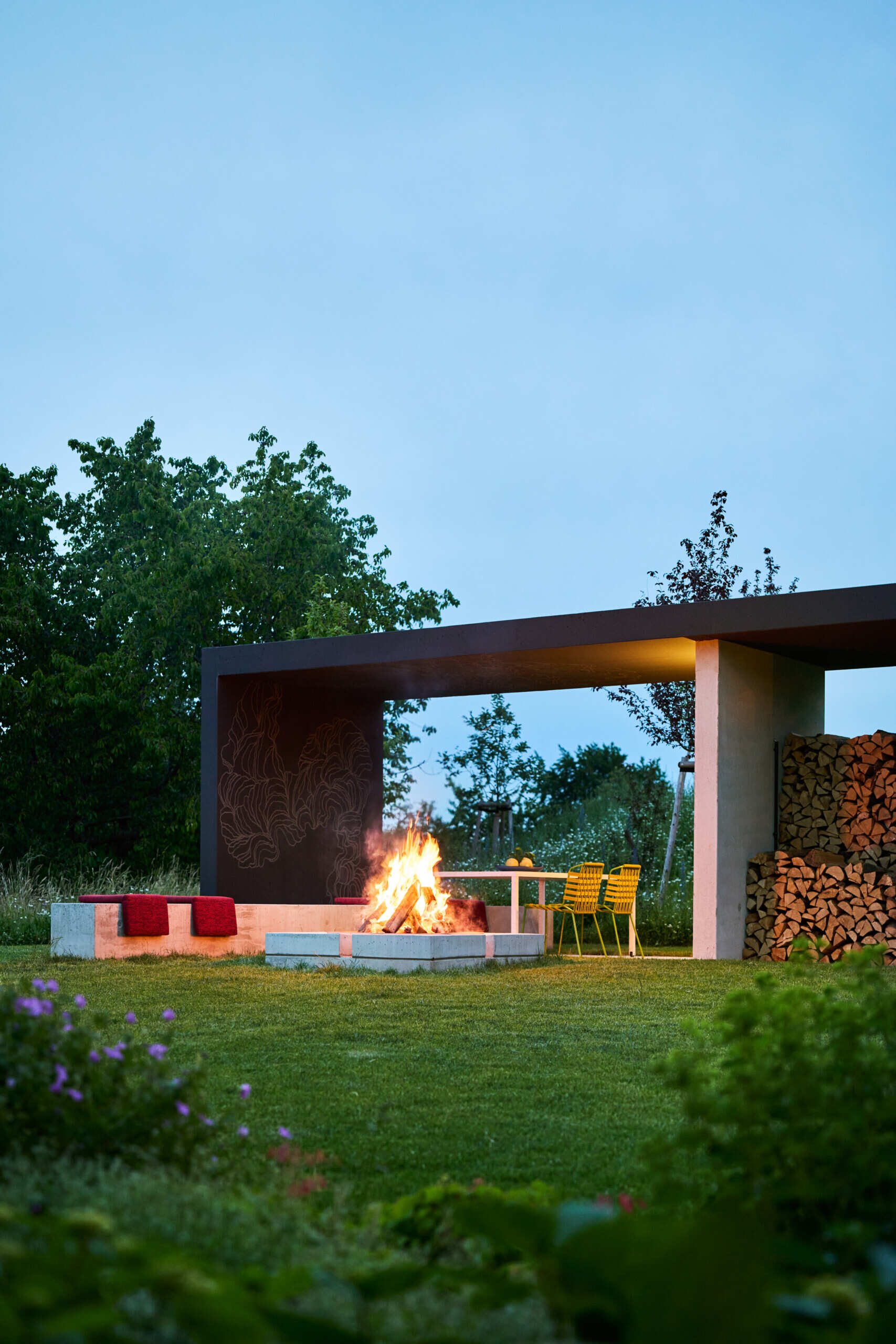 A modern house with a patio, swimming pool, and firepit.