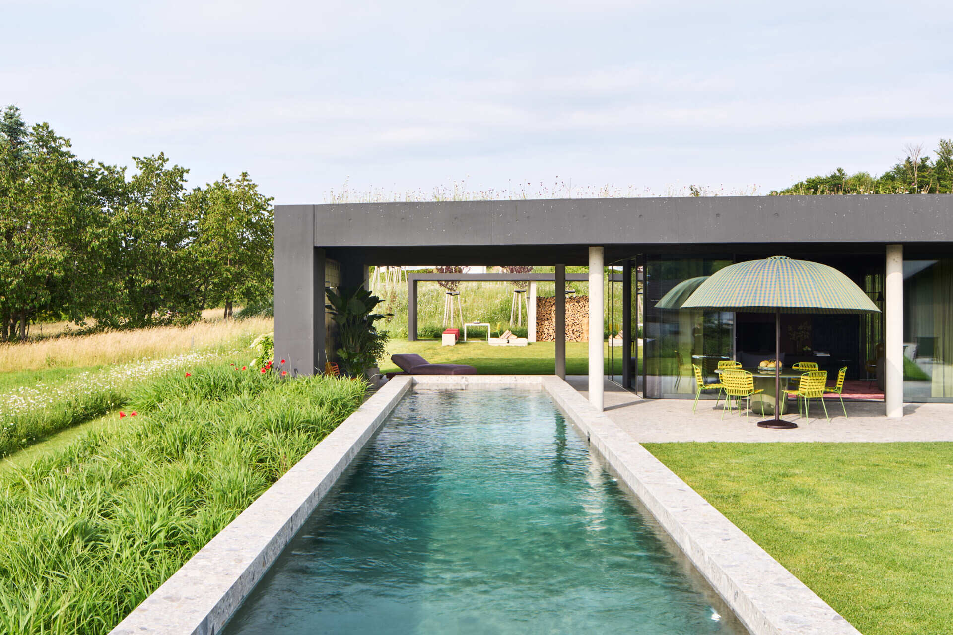 A modern house with a patio, swimming pool, and firepit.