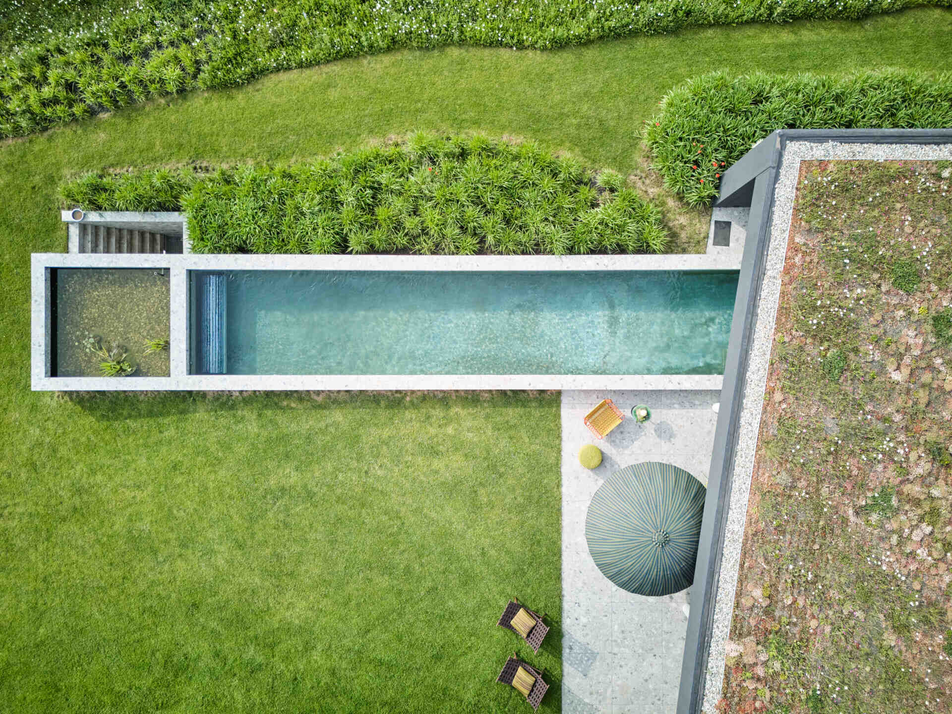 A modern house with a patio, swimming pool, and firepit.