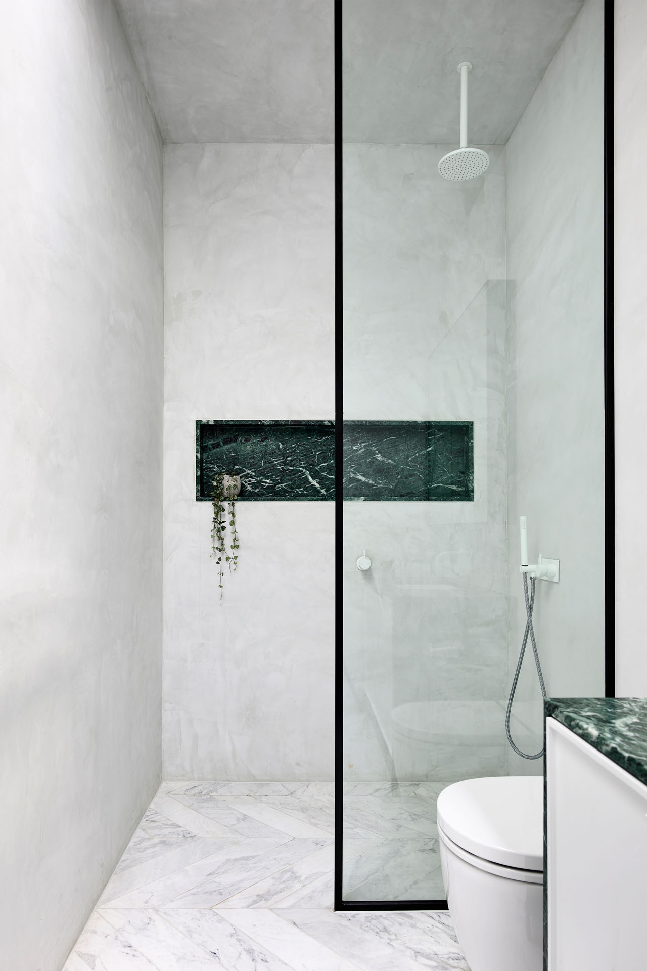 A minimalist bathroom with a black framed shower screen and built-in shelf shows how simplicity can still feel elevated and intentional.