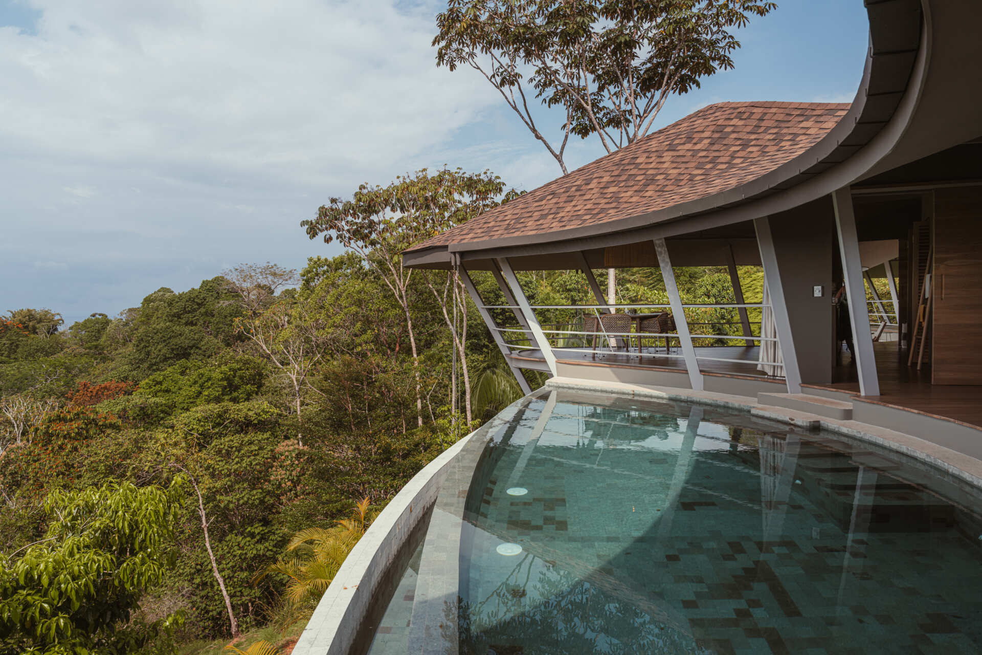 The pool stretches toward the horizon, blending visually with the sky and ocean beyond. From above, its circular reflection forms an eye-like shape, inspiring the name Ojo de Nila. This gesture reinforces the idea of the home as an observer of its surroundings, always engaged with the landscape it inhabits.