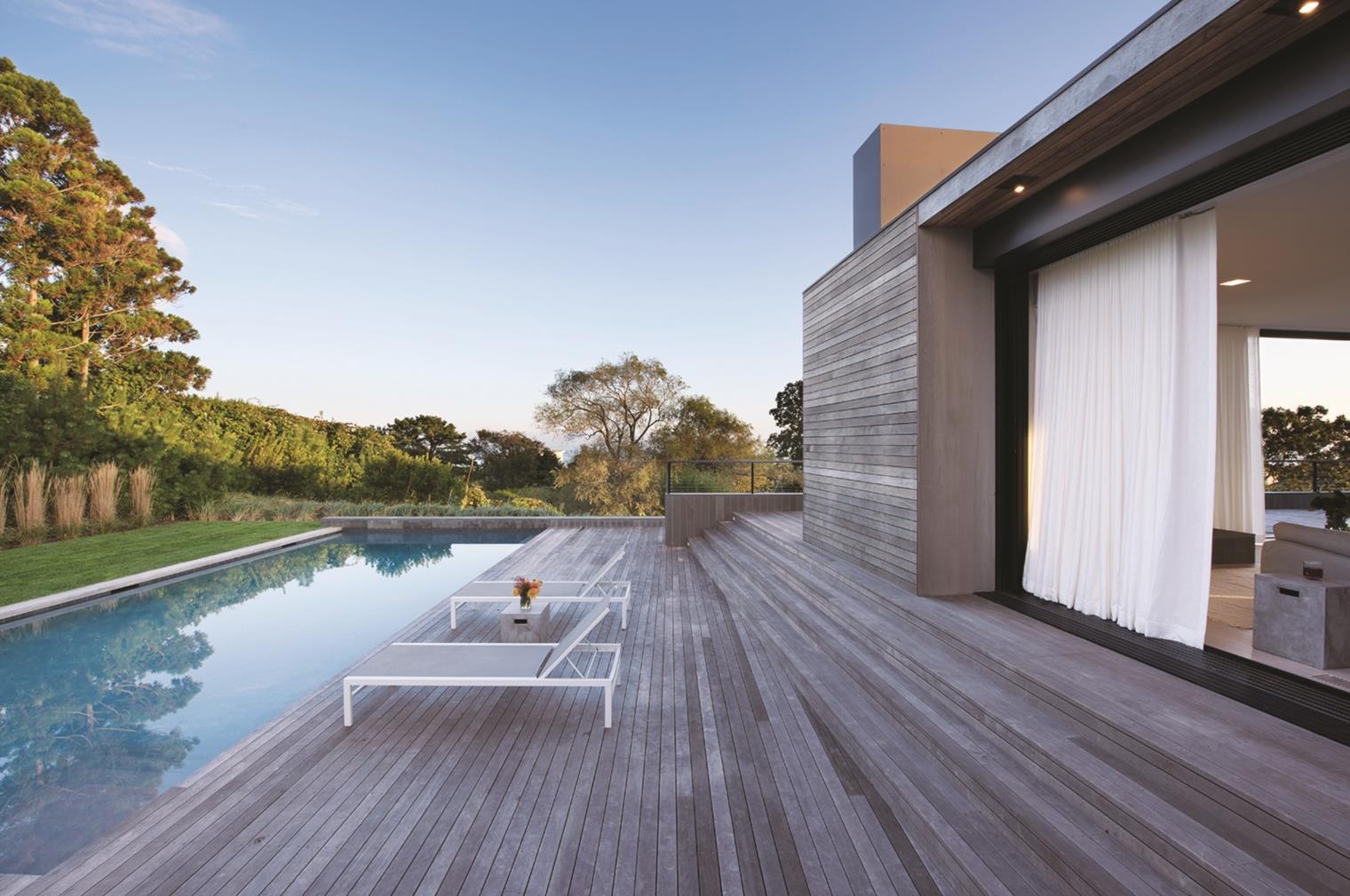 Las cortinas ligeras suavizan el aspecto de la madera y se mueven con la brisa, añadiendo un ambiente suave a este refugio junto al mar.