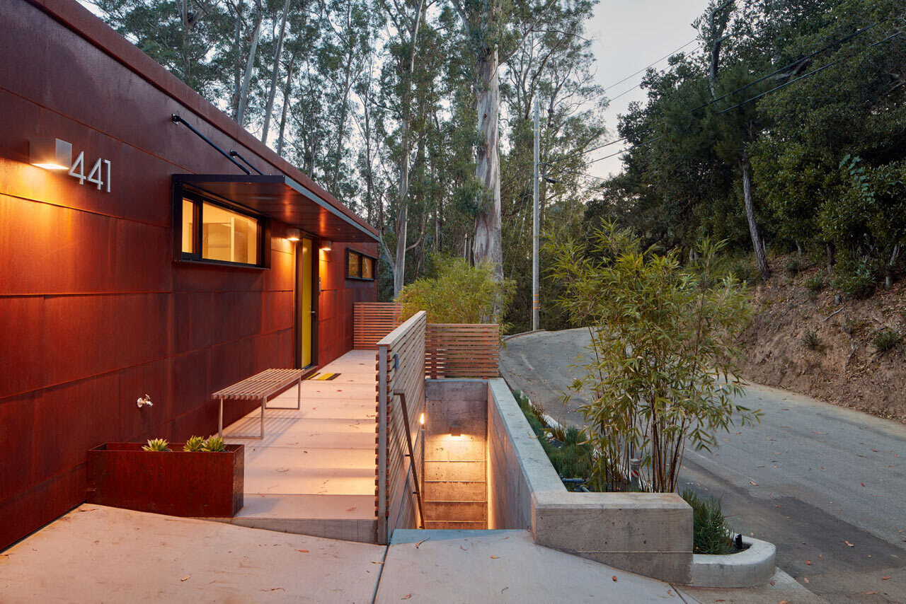 Revestida con acero corten, esta casa en la ladera de Mill Valley hace una declaración con atrevidas puertas pivotantes amarillas que contrastan con el exterior resistente.