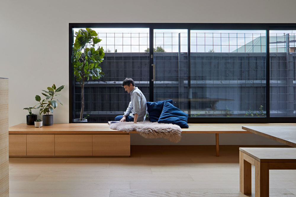 A 29 foot wrap around bench sits beneath sliding glass doors, connecting the kitchen to the garden and shaping daily family life.