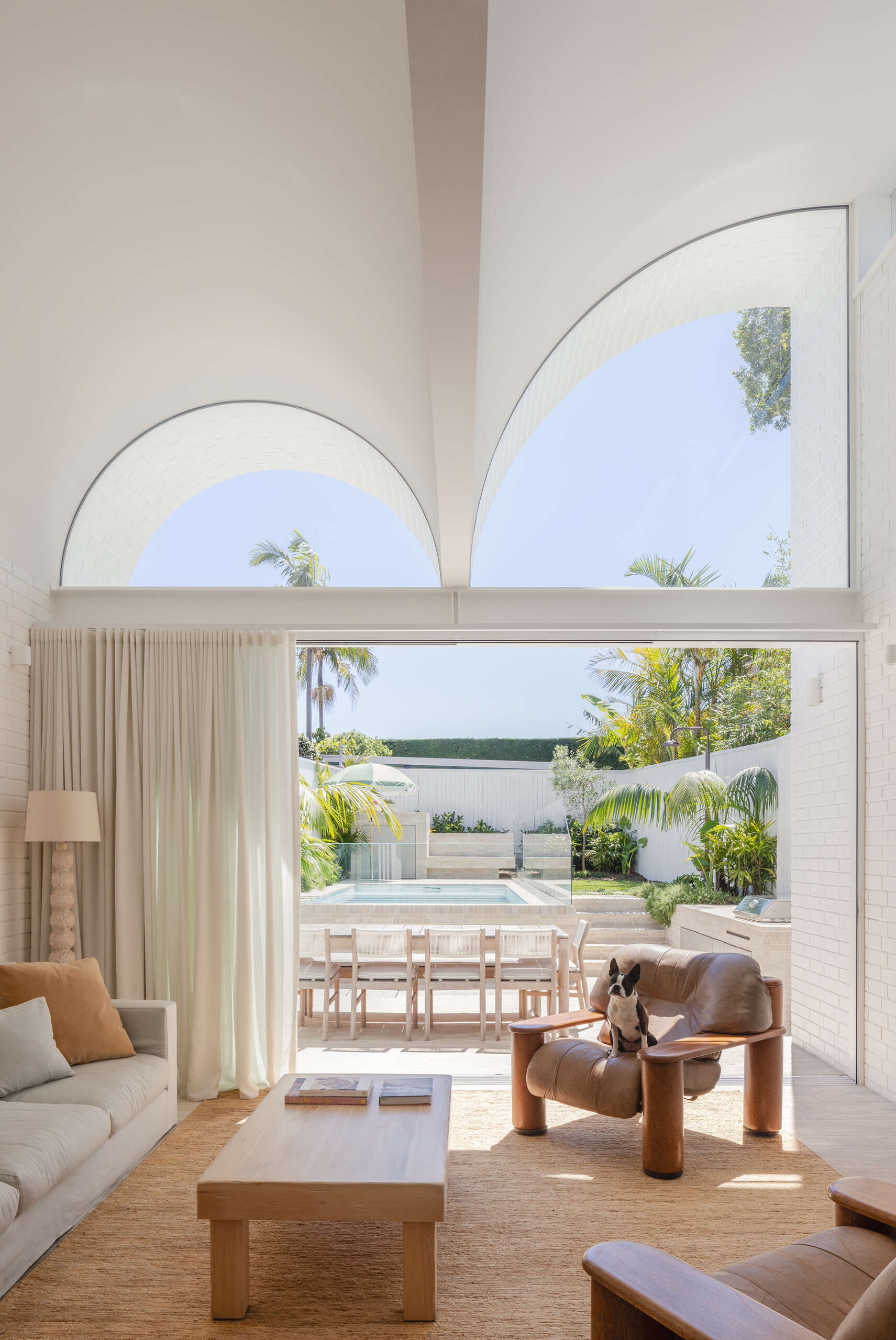 Entry into the house begins with a moment of compression. A framed garden view and a strong brick axis draw the eye upward.

As you move inside, the living area opens dramatically. The scale feels far more generous than the facade suggests, shaped through careful detailing rather than size alone.