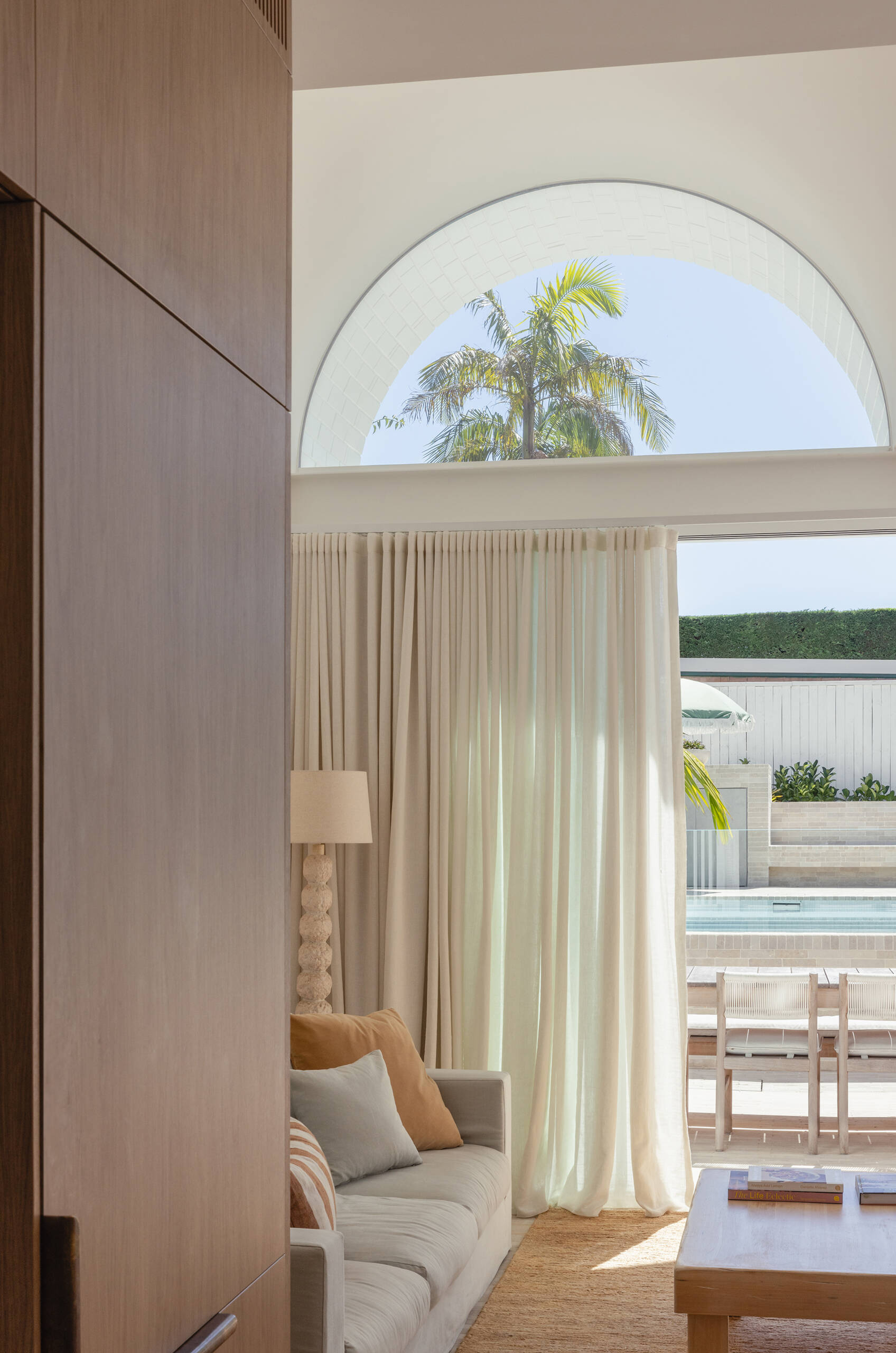 Entry into the house begins with a moment of compression. A framed garden view and a strong brick axis draw the eye upward.

As you move inside, the living area opens dramatically. The scale feels far more generous than the facade suggests, shaped through careful detailing rather than size alone.