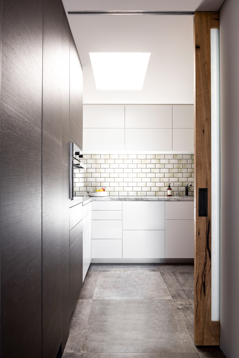 A minimalist kitchen with subway tiles, a large island and concealed pantry keeps the space feeling light and functional.