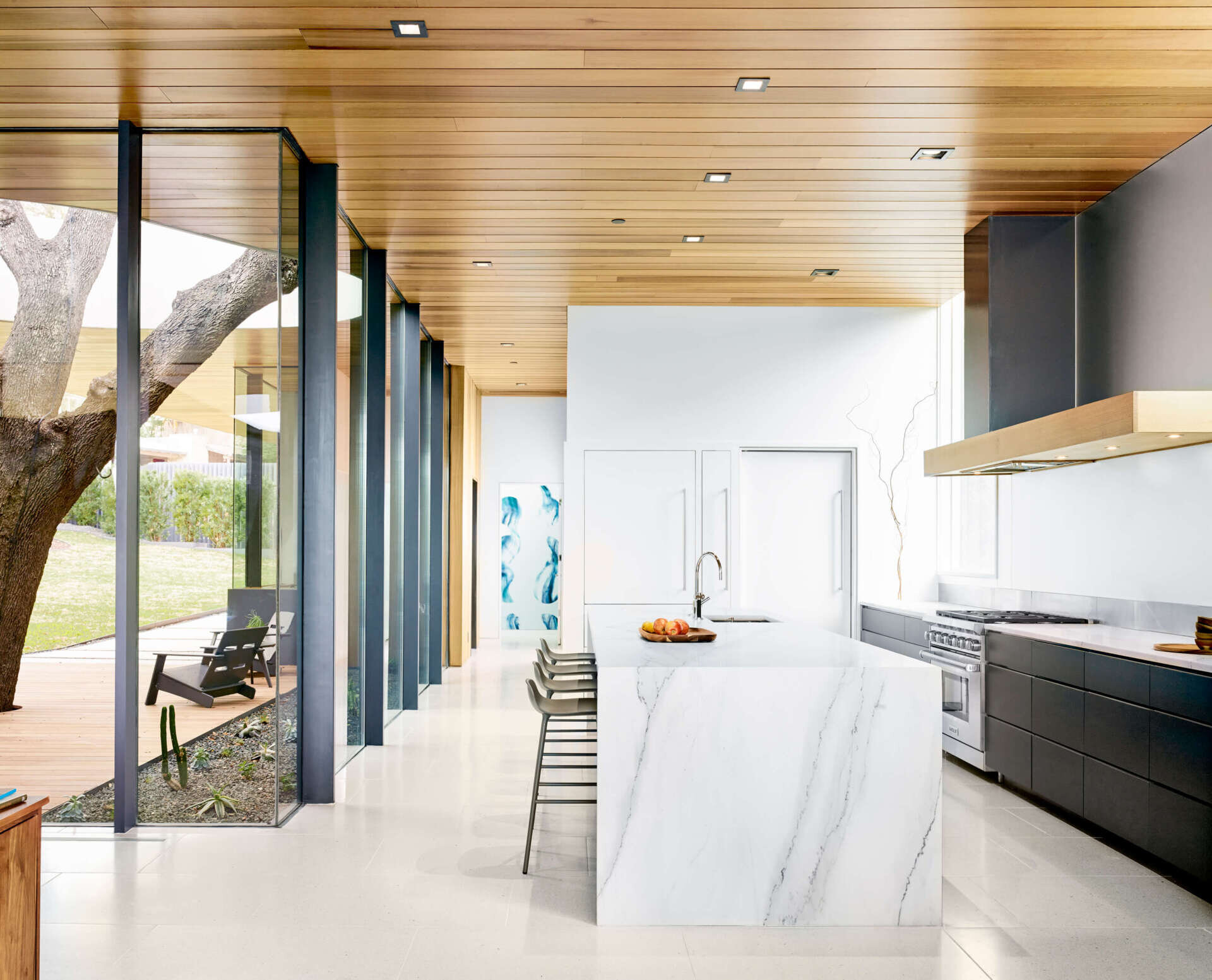 Los gabinetes oscuros y el protector contra salpicaduras de metal agregan contraste a la cocina, equilibrando materiales sofisticados con la funcionalidad cotidiana.