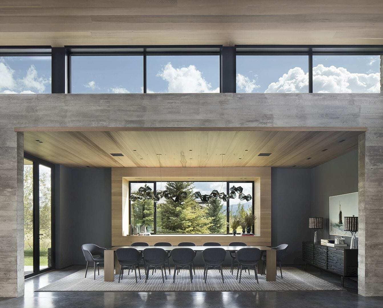 Un espacioso comedor de planta abierta con una mesa para doce personas se encuentra debajo de un tragaluz, lo que aporta una suave luz natural al corazón de la casa.