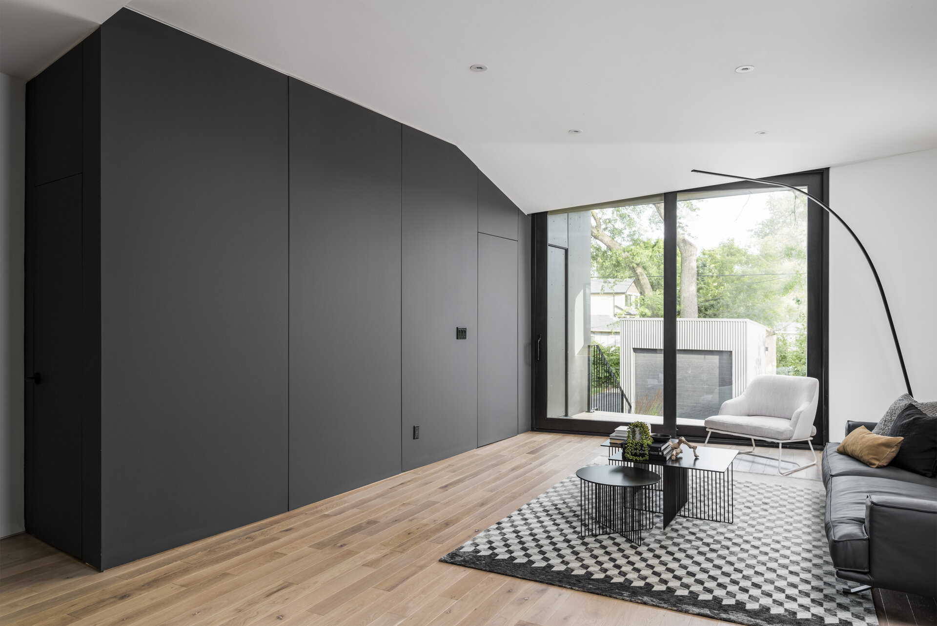 The rear living space features a black accent wall that conceals functional rooms while maintaining a clean, uncluttered aesthetic.