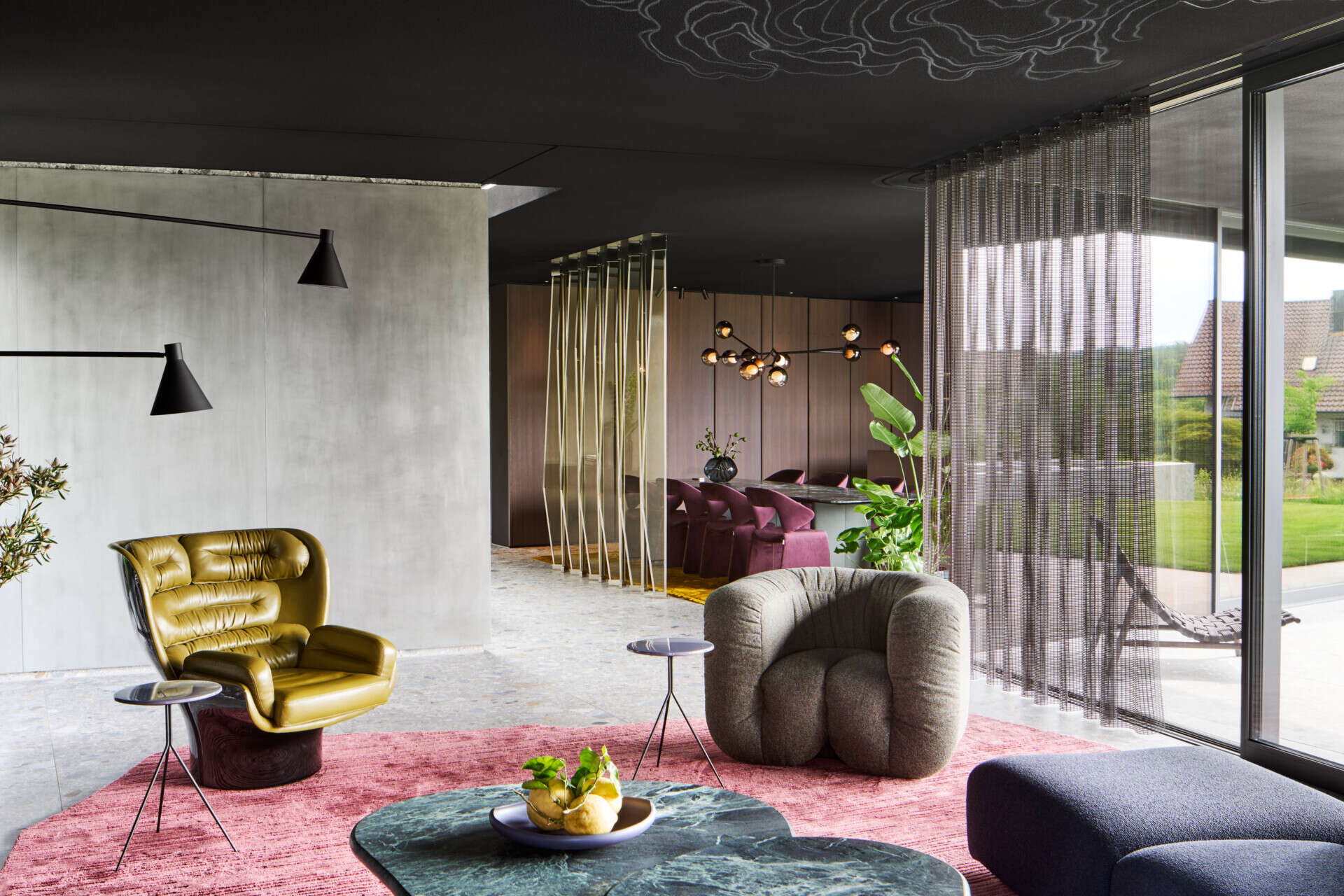 In this living room, a black ceiling stretches across the space, immediately setting the tone. It allows color and material to step forward, turning furniture and sculptural objects into characters within the room. Each element stands on its own, yet remains part of a carefully balanced composition.