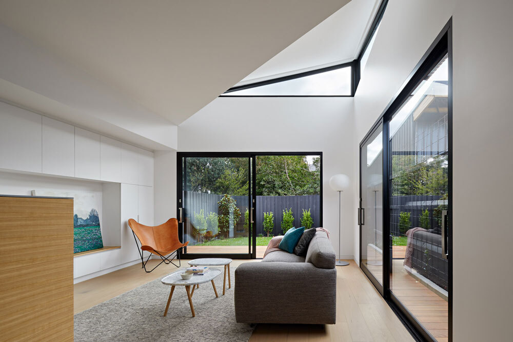 A low timber wall with open shelving separates kitchen and living areas while keeping the space open and connected.