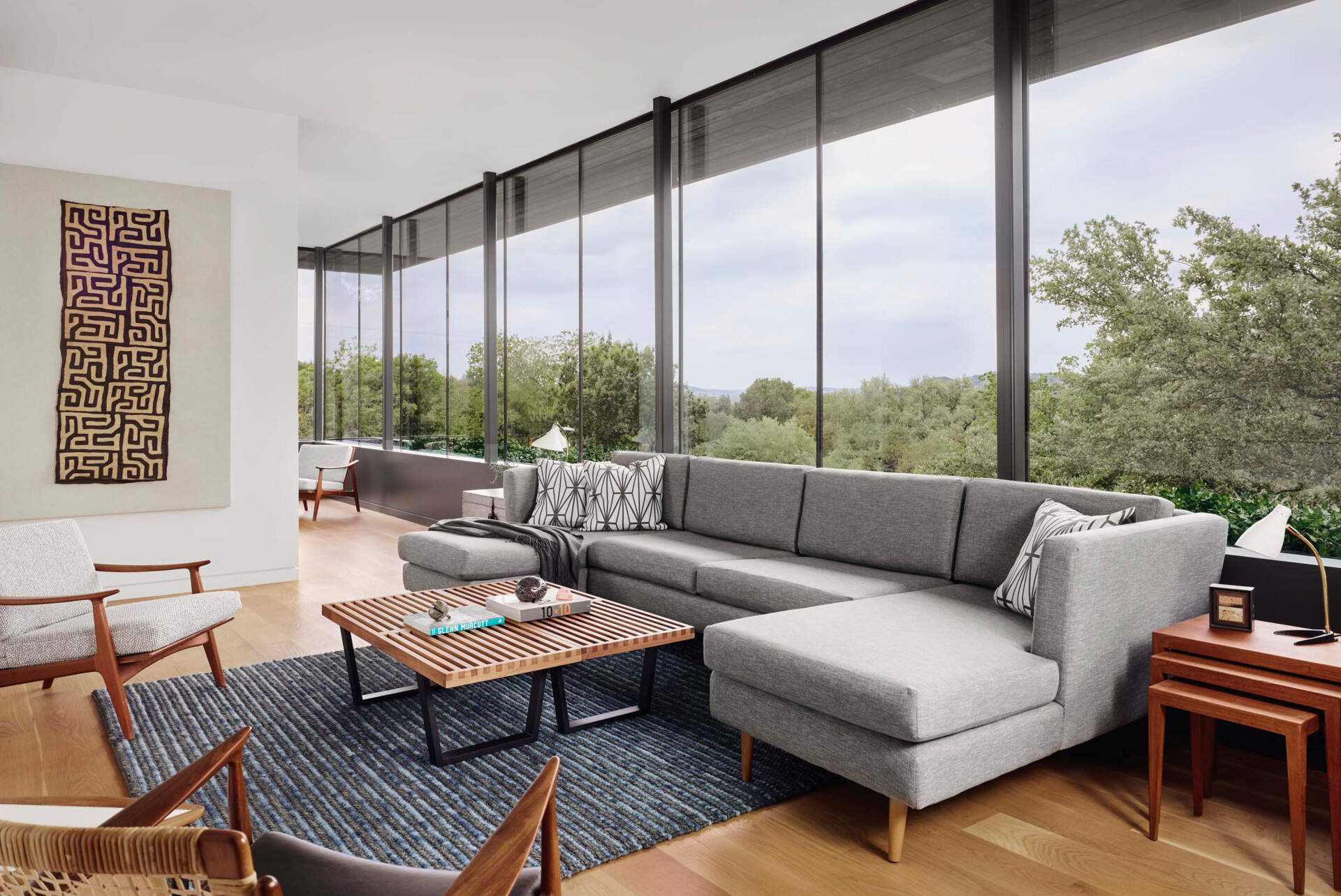 La sala de estar de arriba está inundada de luz natural y ofrece vistas elevadas a través de generosos ventanales de vidrio.