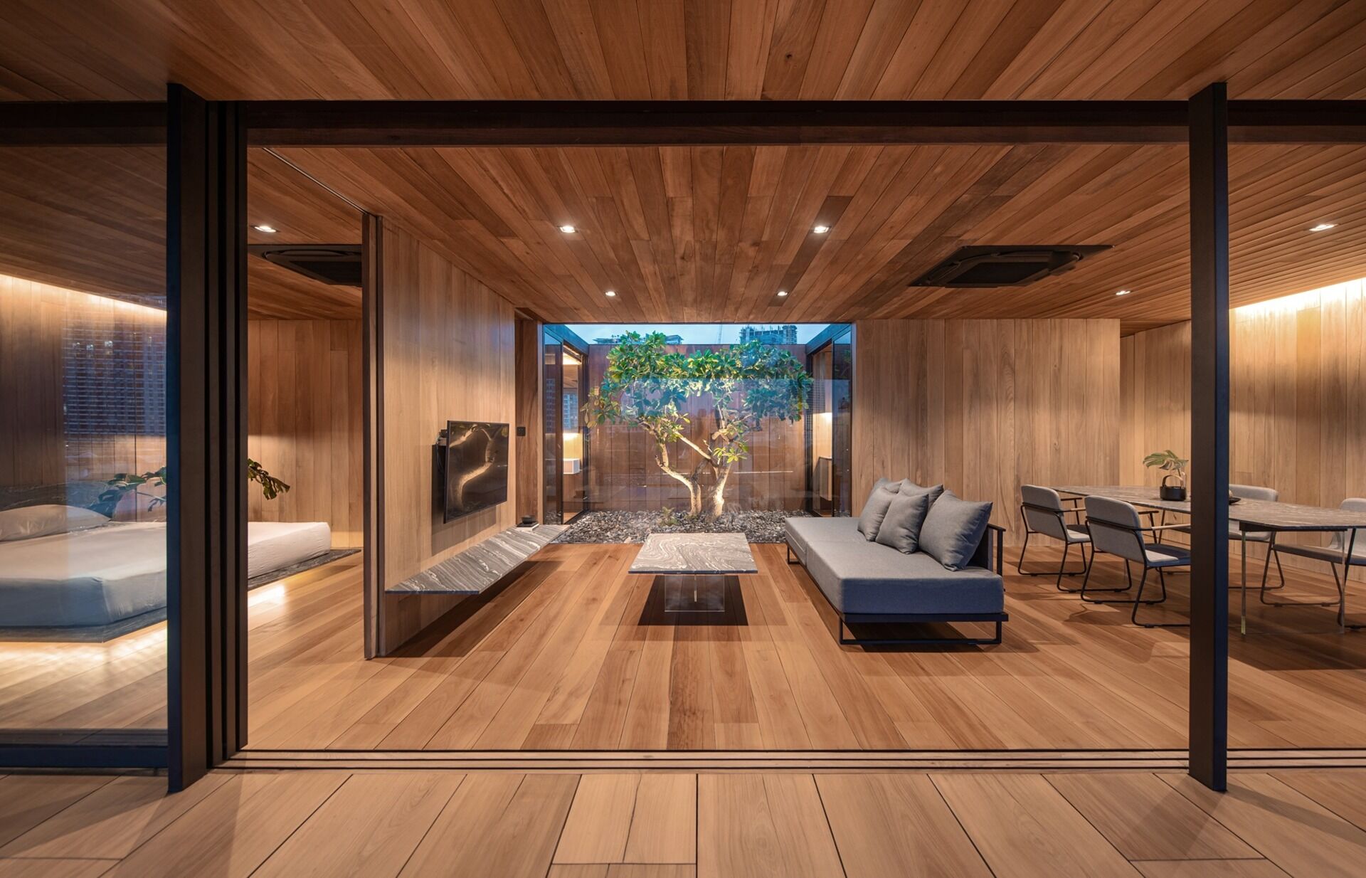 An open plan living and dining space wrapped in wood and glass frames panoramic views of the surrounding city.