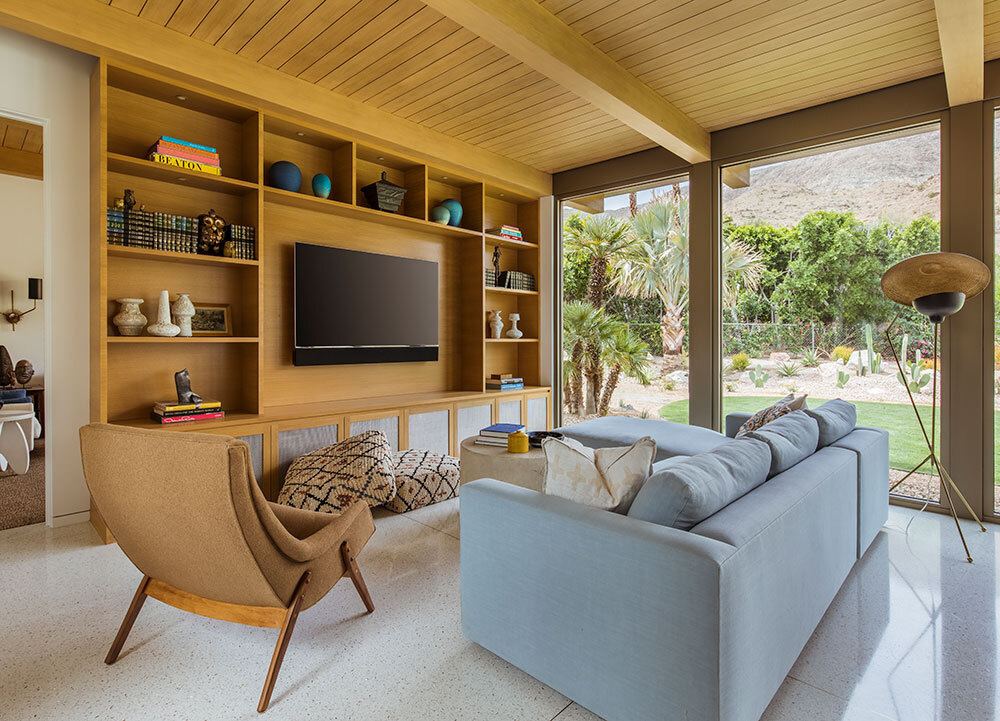 Custom wood shelving surrounds the TV while floor to ceiling windows frame desert views.