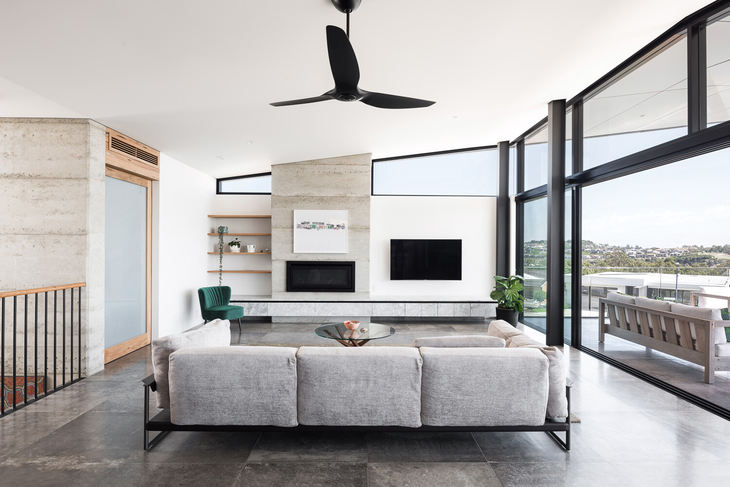 The living room opens fully to the balcony through oversized sliding doors, creating a seamless connection to the river views beyond.