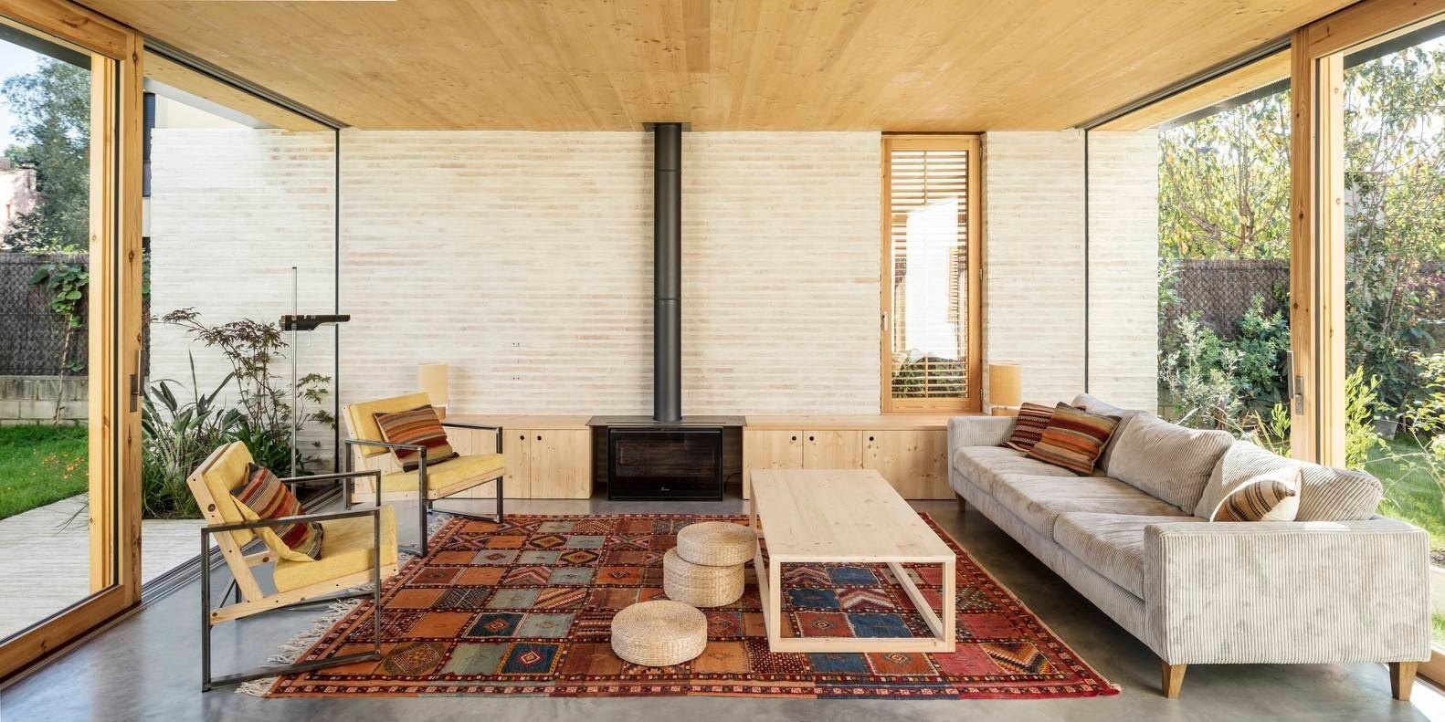 La sala de estar cuenta con una chimenea con almacenamiento incorporado, lo que fundamenta el plan abierto y mantiene el diseño funcional y ordenado.