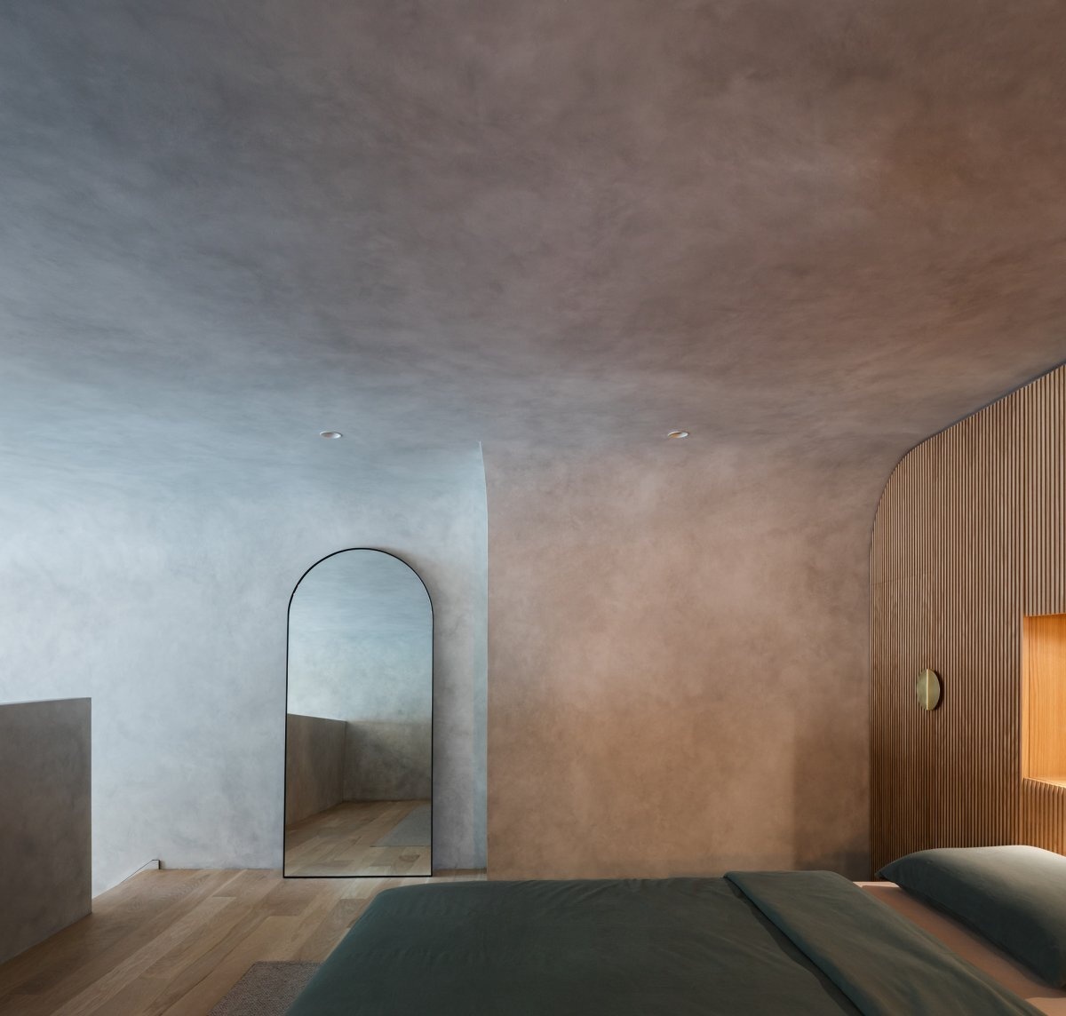 Los techos curvos y una cabecera de madera personalizada con almacenamiento oculto definen este dormitorio en el entresuelo de un loft de Sydney.