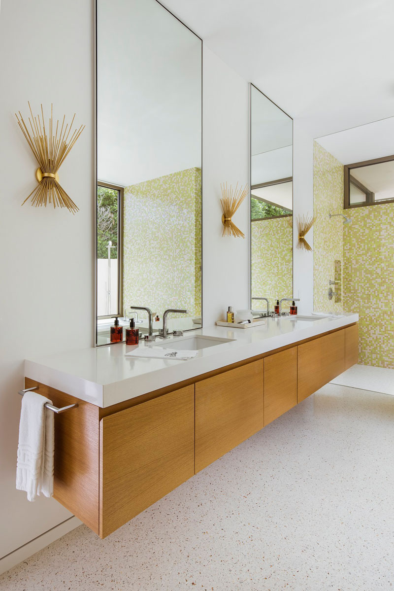A light filled master bathroom with tall mirrors and mid century inspired sconces.