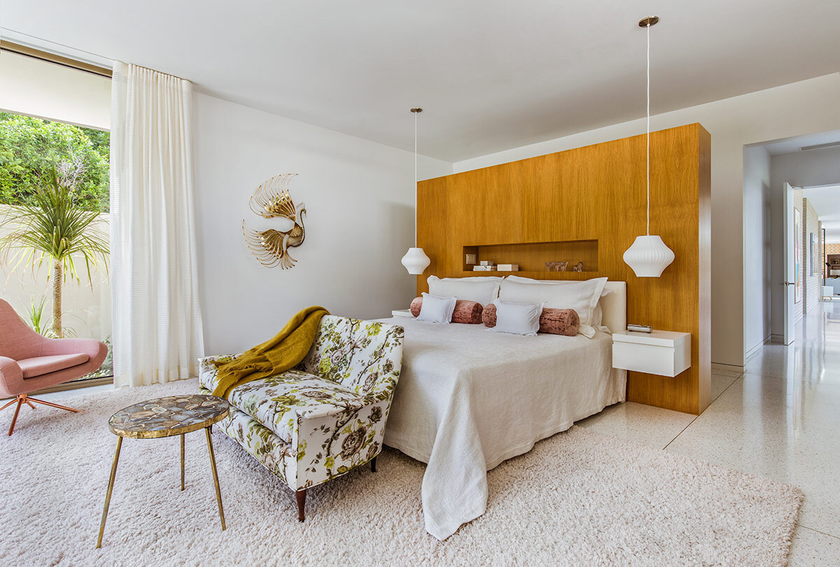 A mid century master bedroom with a wood feature wall and sliding glass doors to a private patio.