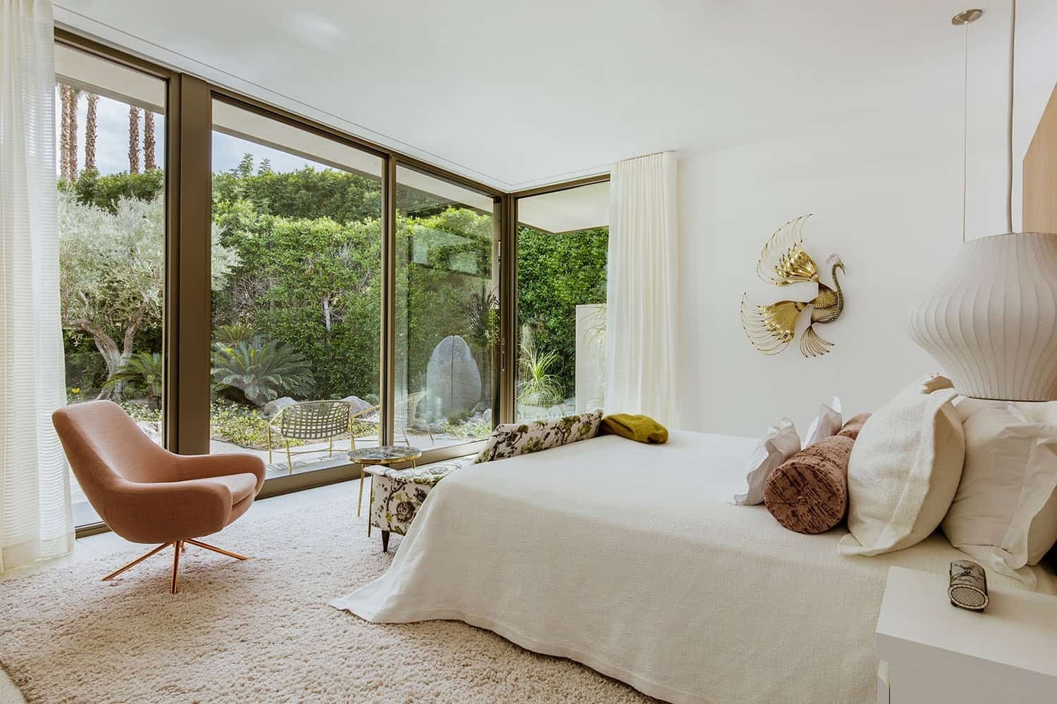A mid century master bedroom with a wood feature wall and sliding glass doors to a private patio.