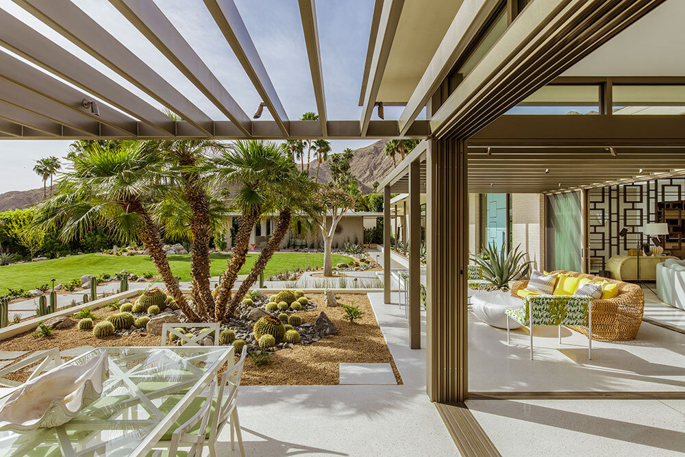 Glass walls open to pergola covered outdoor seating areas in a desert mid century home.