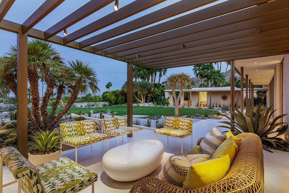 Glass walls open to pergola covered outdoor seating areas in a desert mid century home.