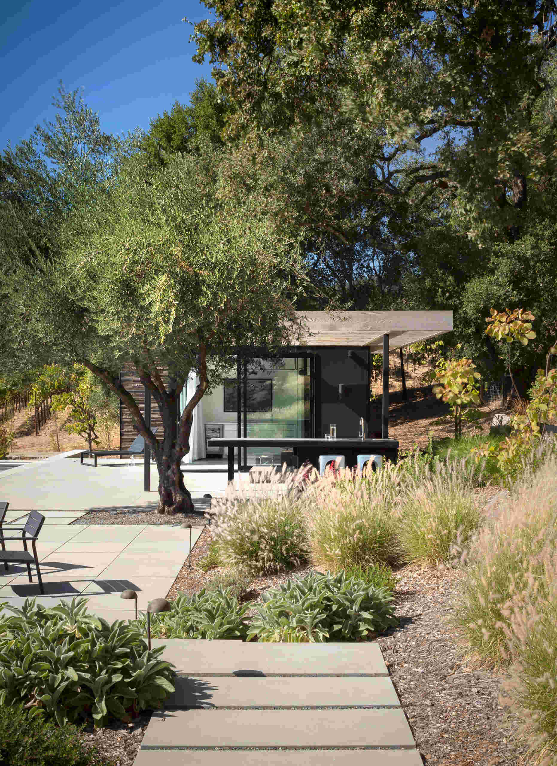 Large sliding doors connect the living room to a semi covered terrace with an outdoor kitchen and open views.