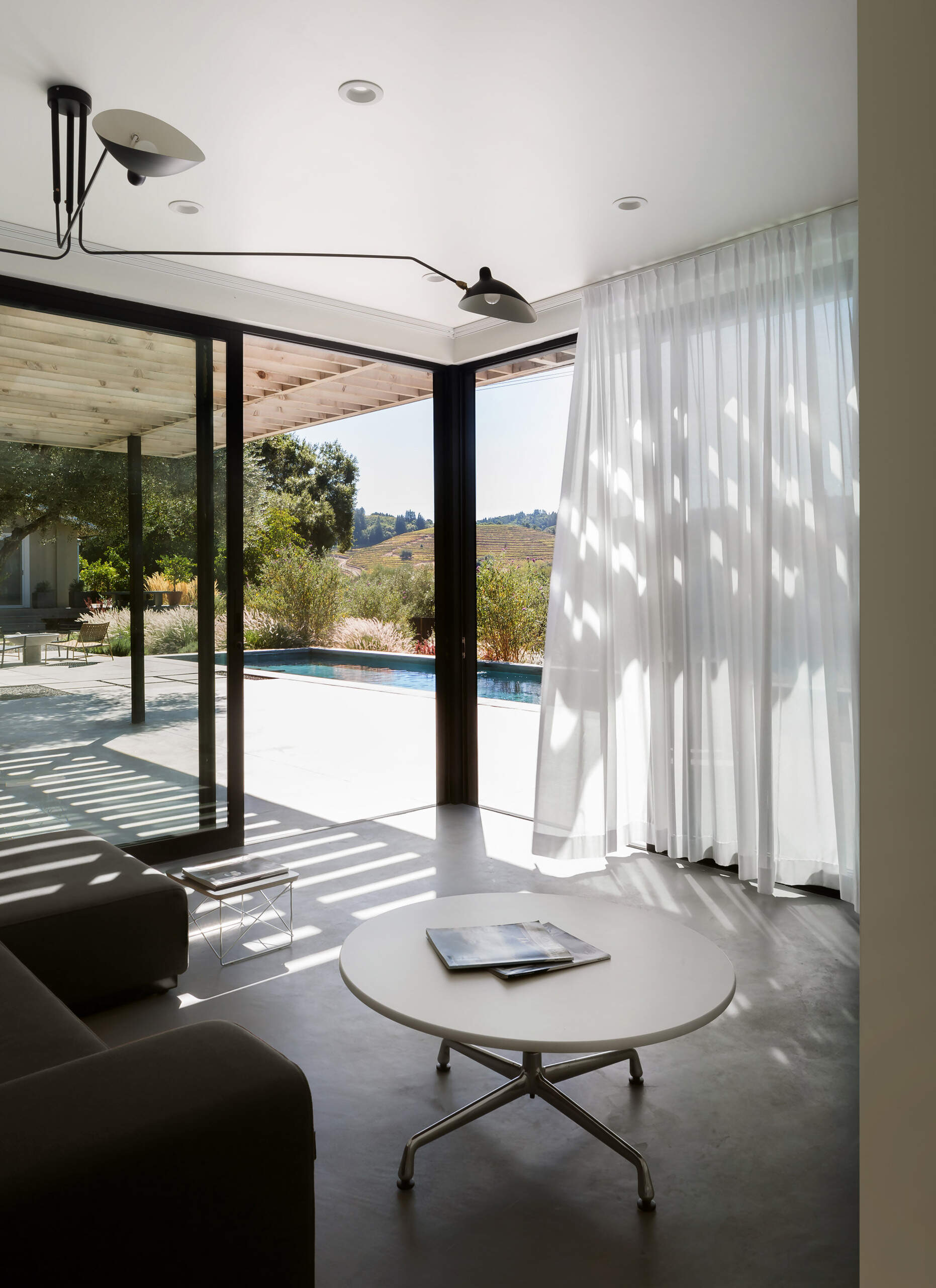 Large sliding doors connect the living room to a semi covered terrace with an outdoor kitchen and open views.