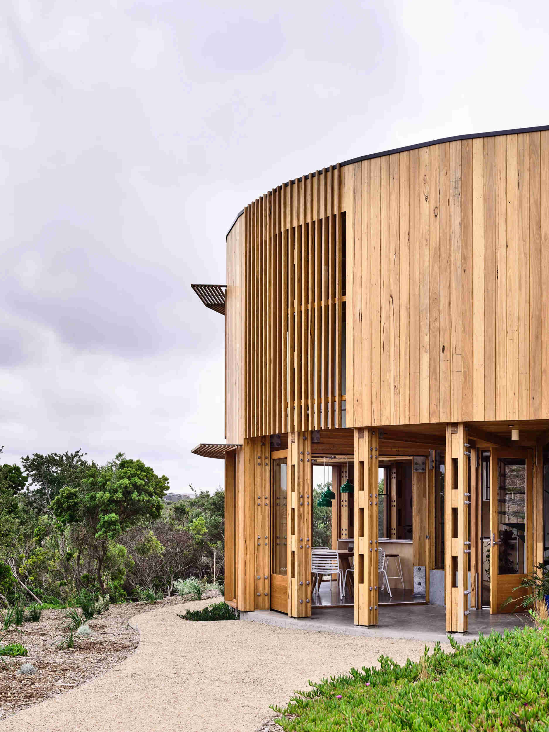 A round beach house with an integrated deck that opens directly to the surrounding sand dunes and bush.