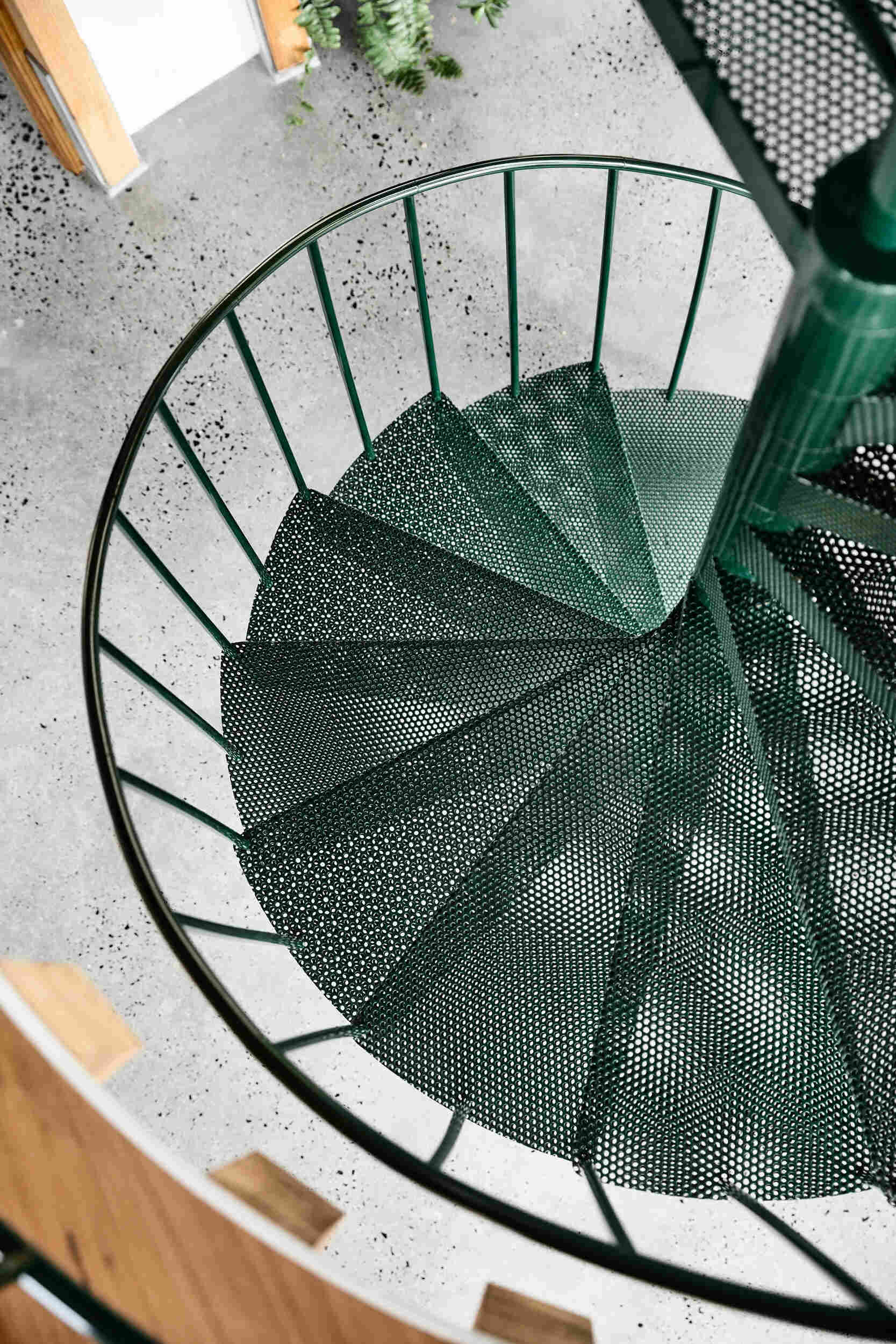 A dark green spiral staircase at the centre of a circular beach house interior.