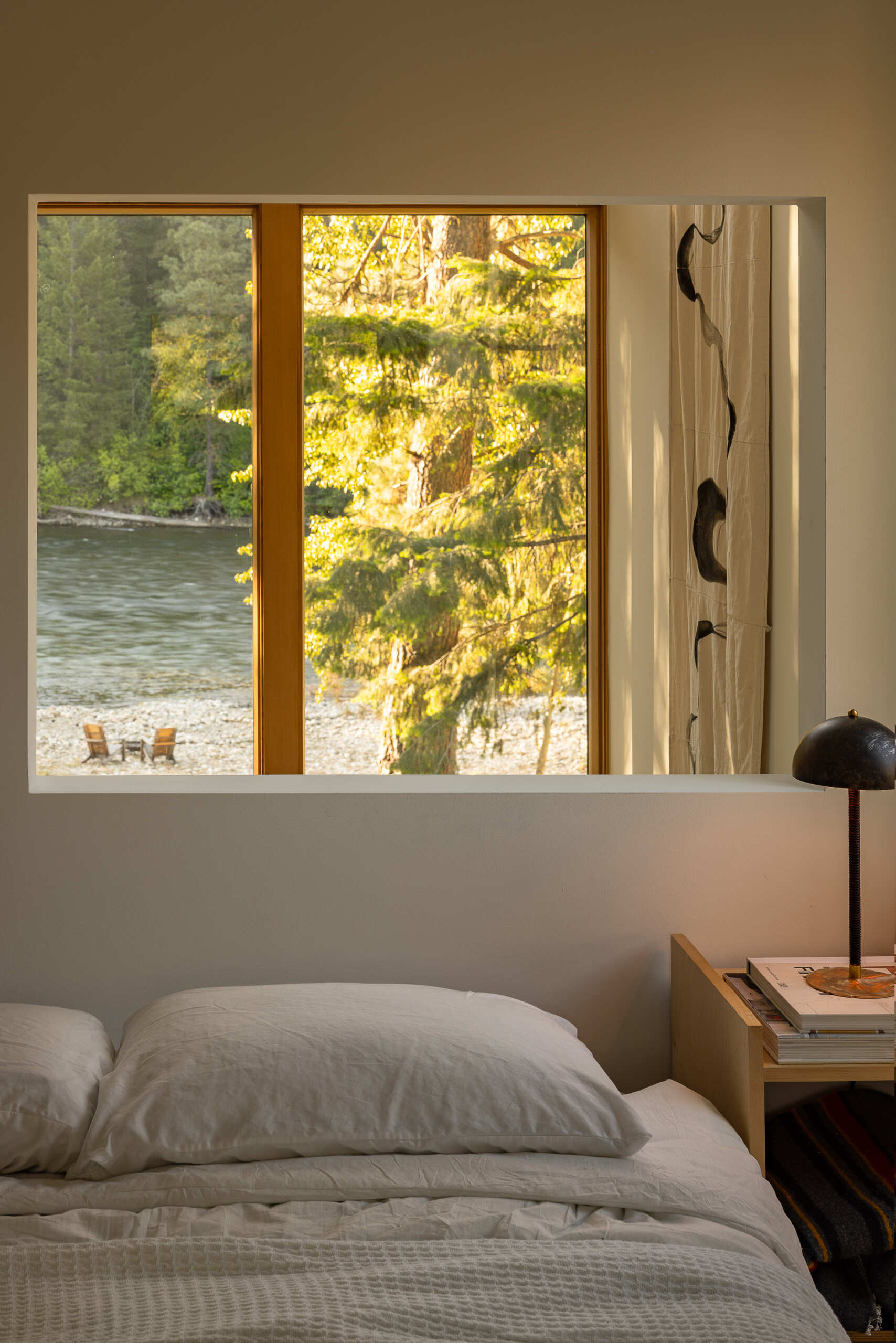 The main bedroom occupies the upper level alongside the office. From here, the view portal reconnects the private space with the shared living area below and the landscape beyond.