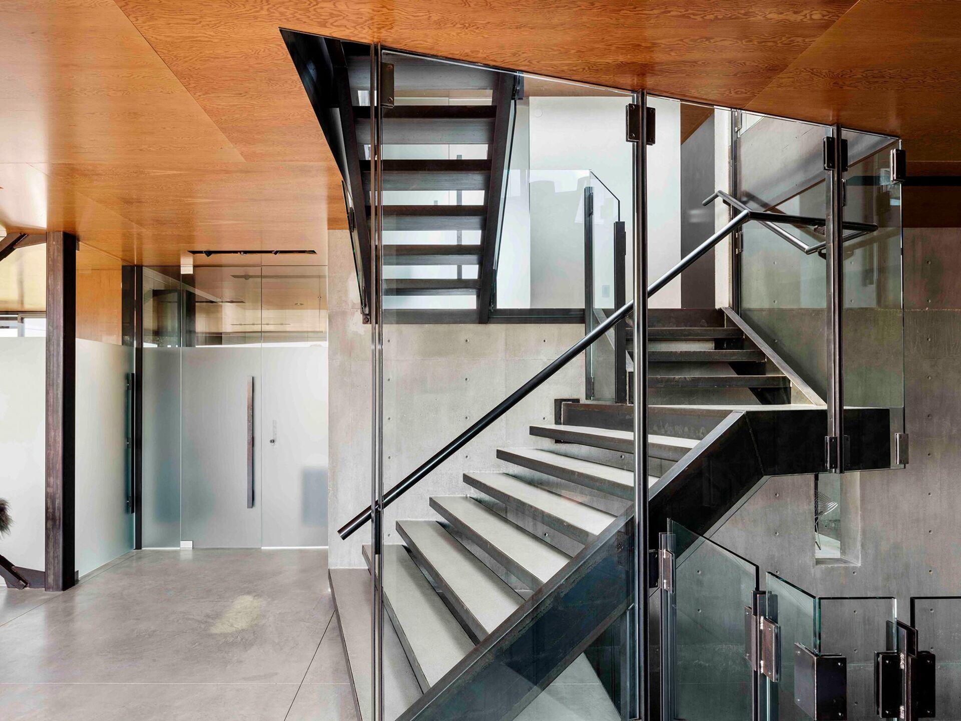 Una escalera central rematada con un tragaluz trae luz natural a la casa de tres pisos, iluminándola desde adentro hacia afuera.