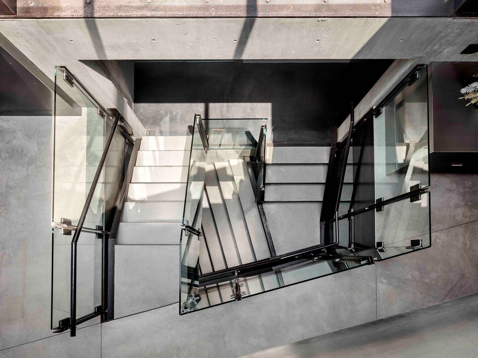 Una escalera central rematada con un tragaluz trae luz natural a la casa de tres pisos, iluminándola desde adentro hacia afuera.