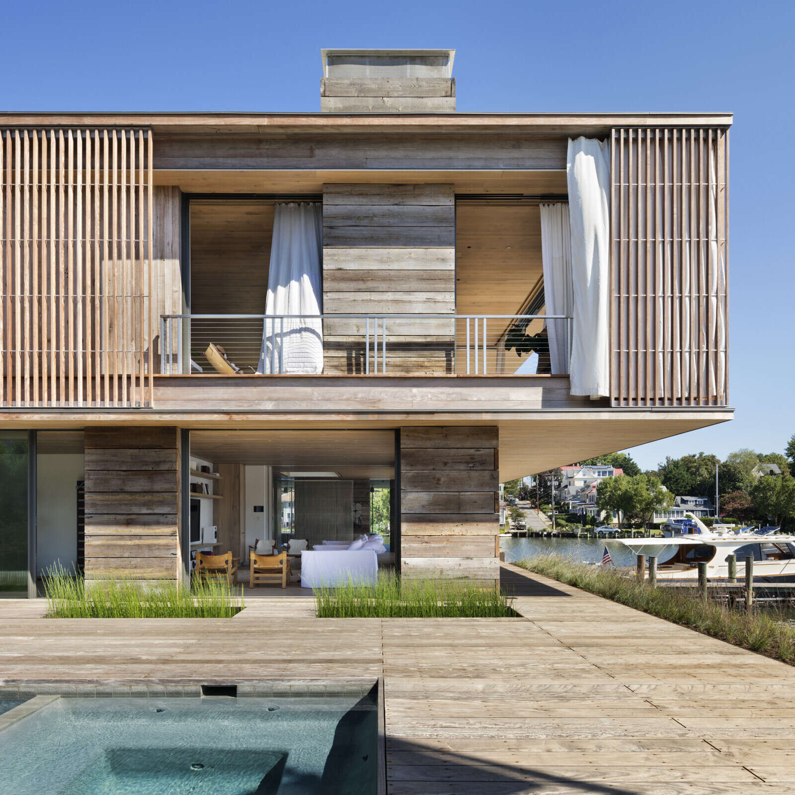 Cantilevered decks, deep overhangs, and layered Ipe screens define the upper level of this modern Chesapeake Bay home.