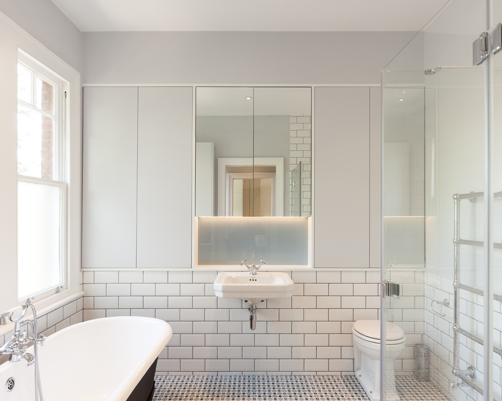 Una bañera independiente negra se destaca sobre los azulejos blancos del metro y la lechada oscura.