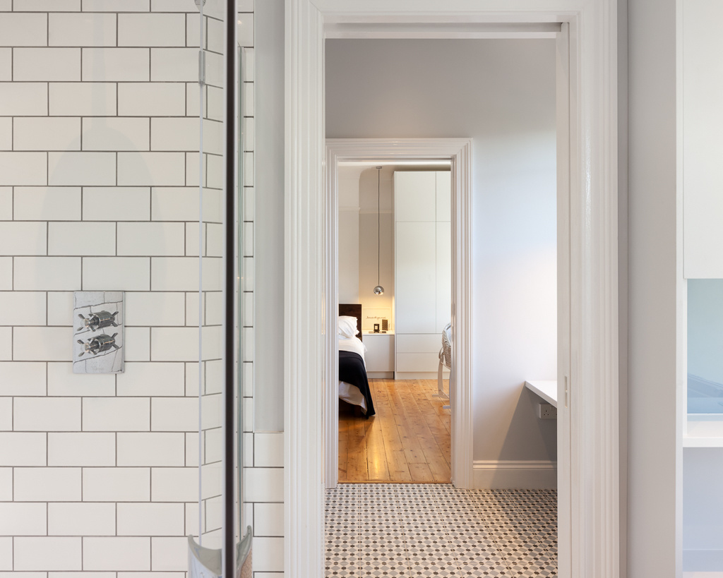 Una bañera independiente negra se destaca sobre los azulejos blancos del metro y la lechada oscura.